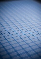 Close up view of a uniform blue gridded paper showing the texture and pattern of the lines, suitable for educational or office stock photography.