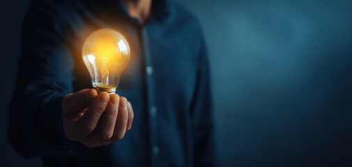 The light bulb in hand glowing idea concept against a dark blurred background