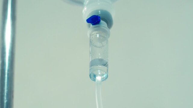 Close-up view of a slow intravenous infusion with a blurred white background in a hospital room. health and medical concept