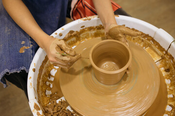 potter's wheel and girl's hands sculpting clay	