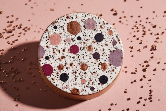 Round, decorative, speckled disc on blush pink background - Powered by Adobe