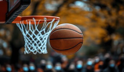 Basketball mid air about to go through hoop with blurred crowd background sport game