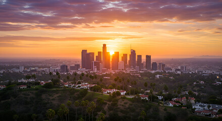 Fototapeta premium Los Angeles skyline at sunrise with residential areas and palm trees in the foreground. Panoramic view of the city with a dramatic sunset.