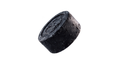 Dark hockey puck with a design on top, isolated against black background