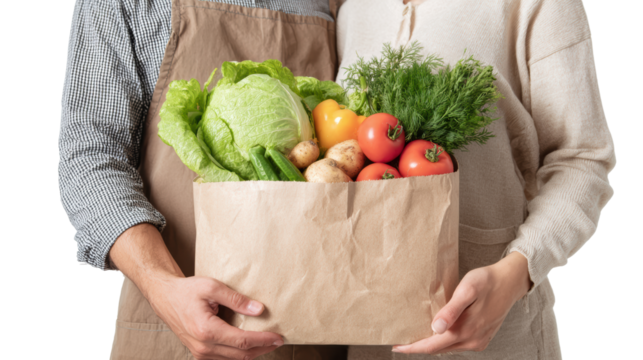 Couple holding a paper bag filled with fresh vegetables, showcasing healthy lifestyle choices.