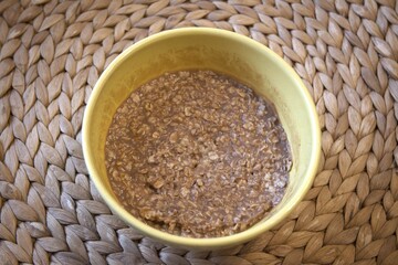 Close-up of creamy chocolate oatmeal served in a yellow bowl. Nutritious breakfast idea with oats, cocoa, and wholesome ingredients.