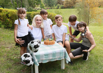 Children Celebrate a Festive Birthday Party Outdoors With Cake, Laughter, and Soccer Balls in a Lush Green Park on a Sunny Day