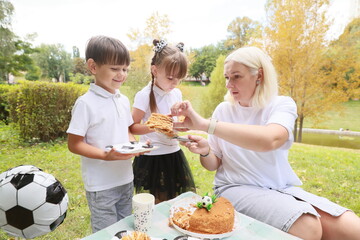 Children Celebrate With Cake and Laughter in a Sunlit Park During a Joyful Outdoor Birthday Gathering Amidst Vibrant Autumn Foliage