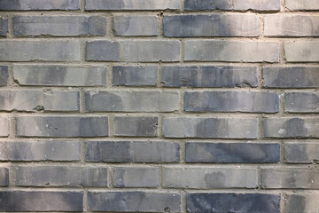 Close up view of a weathered blue gray brick wall with subtle shadows and light highlights creating a textured surface