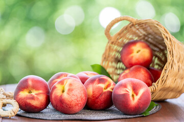 Fresh peach drop from bamboo basket on blurred greenery background, Peach fruit in Bamboo basket on wooden table in garden.