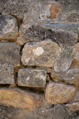 Close up texture of an old weathered stone wall showing irregular shapes and rough surfaces of natural building materials