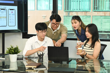 Fototapeta premium Group of business people working, the team are sitting at a board room table looking at a laptop computer.