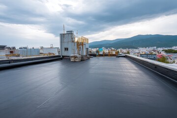 Durable epdm rubber roofing material applied on a flat rooftop in an urban setting with a backdrop of mountains and clouds