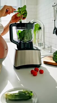 Preparing fresh green smoothie with spinach and cherry tomatoes in modern kitchen