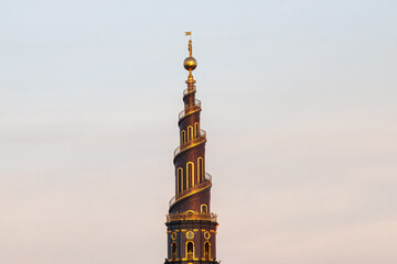 Obraz premium The iconic spiral tower of the Church of Our Saviour in Copenhagen, Denmark highlighted by sunset sun light.
