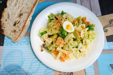 Colorful farfalle pasta salad with boiled egg and bread in castro urdiales, spain