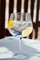 Refreshing gin tonic with lemon and ice cubes on a sunny day