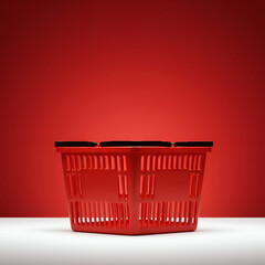 Fototapeta premium Red shopping basket on white surface against a vibrant red background. Empty basket positioned centrally on a plain surface. Retail product display for a grocery store -
