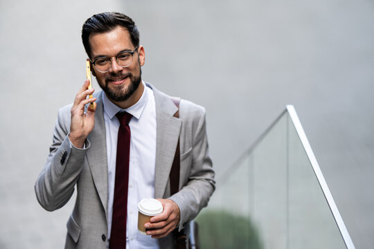 Businessman walking and talking on phone holding coffee