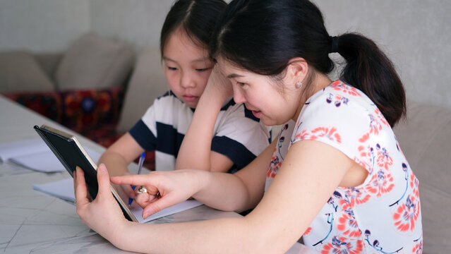 The tutor teaches the child. Home schooling. Mom explains a difficult math topic to her daughter. A woman and a child do their homework