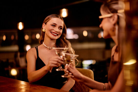 Two Women Toasting With Drinks in a Stylish Bar Setting