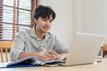 Fototapeta premium Asian attractive man freelancer using laptop device working in house. 