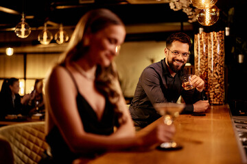 Man Enjoying a Drink at a Bar Engaging in a Friendly Conversation