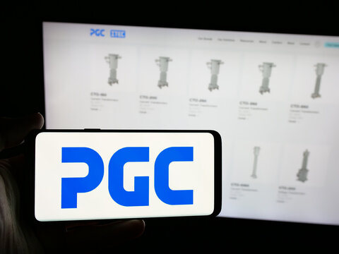 Stuttgart, Germany - 08-22-2025: Person holding smartphone with logo of US company Power Grid Components Inc. (PGC) on screen in front of website. Focus on phone display.