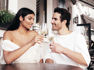 Smiling beautiful woman and her handsome boyfriend. Happy cheerful family. Sexy couple cheering with glasses of red wine at their date in restaurant. Drinking alcohol at veranda cafe