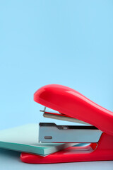 Red stapler with sticky notes on blue background
