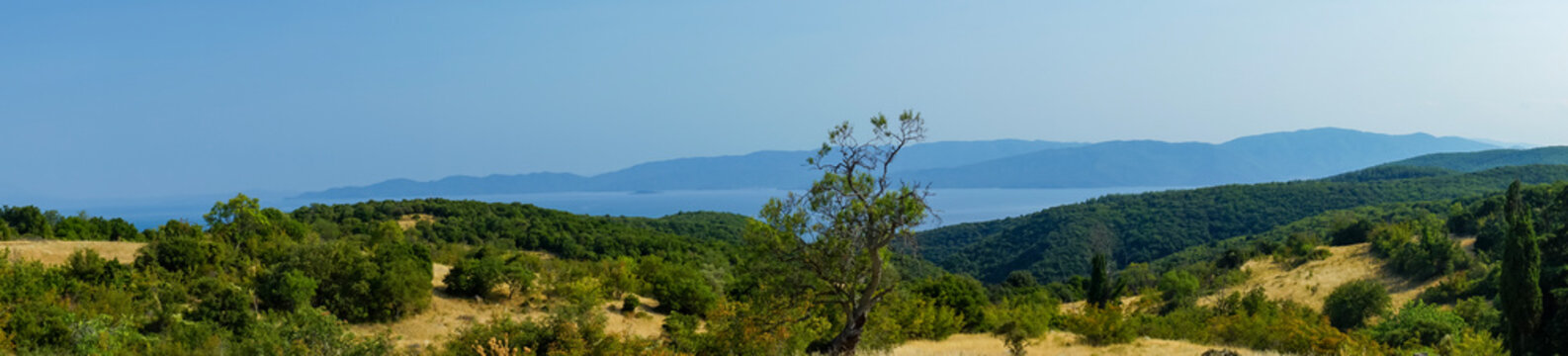 Wide panoramic view of lush green hillside and tranquil sea in Asprovalta, Greece, perfect for tourism, business travel, and nature documentaries.