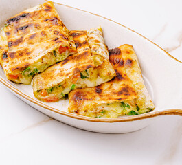 Delicious grilled wraps filled with vegetables and cheese served on a plate