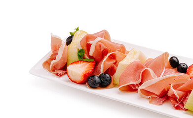 Platter of prosciutto, fresh fruits, and mint leaves displayed artfully