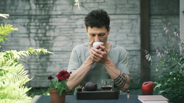 Man drinks Chinese pu erh tea alone in backyard enjoying peaceful morning ritual