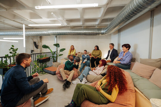 Creative team relaxing and brainstorming on beanbags in modern office - Powered by Adobe