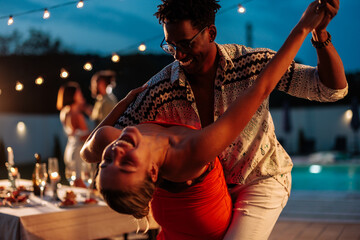 Couple dancing at night party near swimming pool