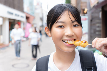 鎌倉観光をしながら食べ歩きをする10代の女性