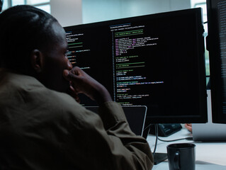 Professional African American male Software Engineer Pointing to desktop computer screen monitor checking line code, examining, planning to development application in Co working Office Space.