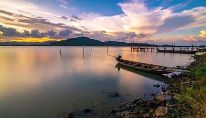 Lake with Boat, Rocky Shore, Mountains, and Sunset