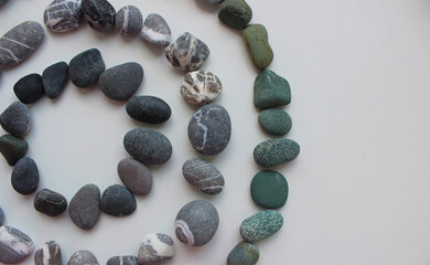 Conical pattern of three circles of smooth, quartz and green stones isolated on white
