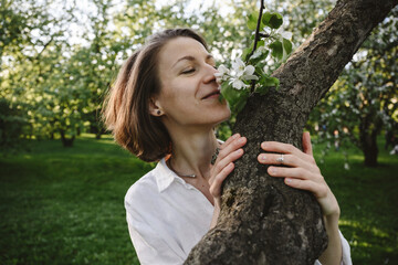 Woman with closed eyes enjoying apple blossom in spring park