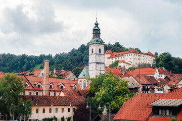 Fototapeta premium Picturesque european old town of Skofja Loka with church tower, red rooftops and historic buildings surrounded by green hills. Slovenia