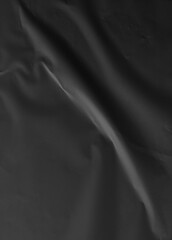 Black crumpled and creased glued paper isolated on a clean background. The textured surface adds depth and character, ideal for modern and artistic design projects. Hoja papel negro mojado.