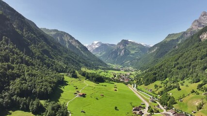 Aerial view of Betschwanden in Glarus Süd, Switzerland, with green alpine valley, scattered chalets, and the majestic Tödi mountain in the background.