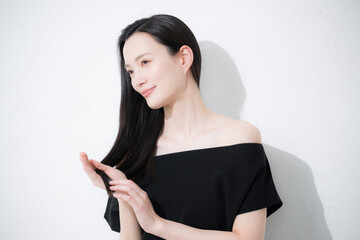 髪の毛の毛先のヘアケアをする女性　トリートメントや枝毛のイメージ © kapinon