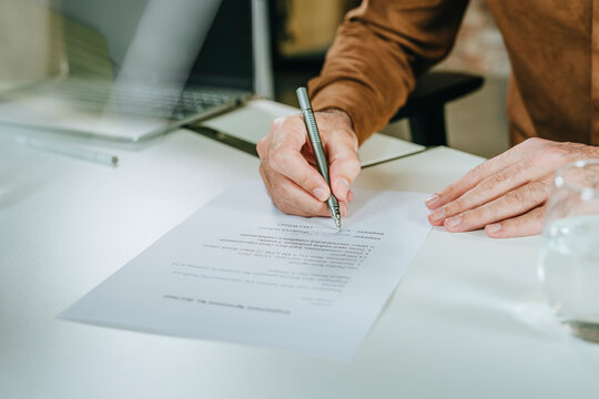 Businessperson signing employment contract at office desk