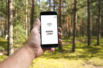 Man holding smartphone showing signal lost in forest
