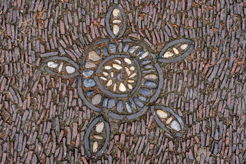 a cobblestone pavement featuring an intricate, symmetrical pattern with alternating dark and light stones forming a geometric design.