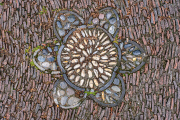 a cobblestone pavement featuring an intricate, symmetrical pattern with alternating dark and light stones forming a geometric design.