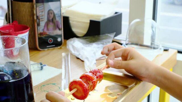A teenager eats Dessert Strawberries in glass. Berries in sugar syrup. Nibble on a delicious sweet dessert. Korean cuisine. A lover of Korean traditional food. A trend among teenagers